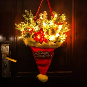 Luminous Christmas hat decoration with pine needles and LED lights on a wooden door