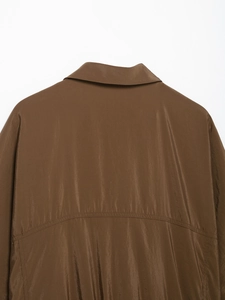 Détail de l'empiècement au dos d'une chemise safari marron en tissu satiné