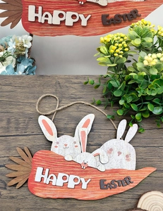 Macro view of wooden carrot-shaped sign with white rabbits and Happy Easter text