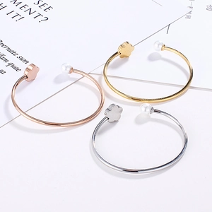 Detailed view of adjustable metal bangles with dainty flower accents and white pearls