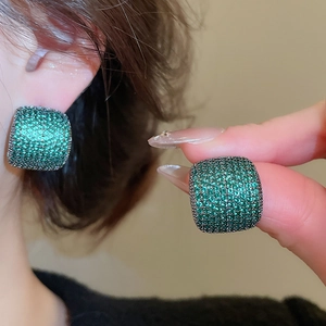 Macro detail of luxury emerald green zircon pavé square stud earrings on silver needle