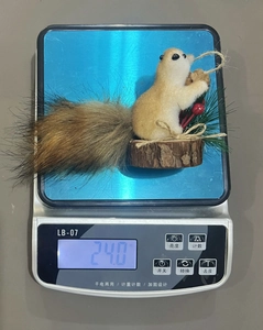 Detailed view of handmade squirrel ornament with pine needles and red berries on a scale