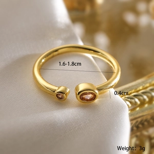 Macro shot of gold-plated open ring with amber zircons on white silk background