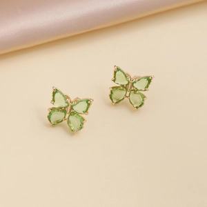 Detail of gold butterfly earrings featuring vibrant green crystal stones on silk