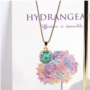 Detail of teal faceted gemstone pendant with gold-tone lace border on elegant necklace