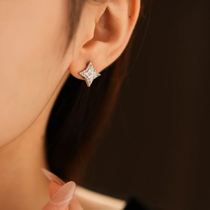 Gros plan de boucles d'oreilles en argent en forme d'étoile avec zircons sur l'oreille