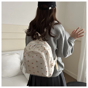 Back view of a white floral mini backpack styled on a model in a casual outfit