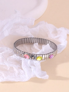 Macro detail of elastic stainless steel bracelet with green, pink and purple gemstones