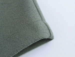 Close-up of green wool blend fabric texture and stitching details on the winter coat sleeve