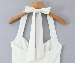 Detail of elegant white halter dress back with a large bow tie on a wooden hanger