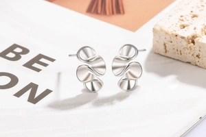 Macro shot of silver irregular wavy stud earrings with polished mirror finish details