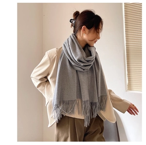 Close-up of a soft grey cashmere-like scarf featuring elegant tassel details for winter
