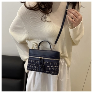 Detail of a vintage navy blue tweed crossbody bag worn by a model in a white sweater