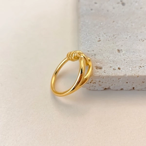 Primo piano di un anello in acciaio inossidabile dorato con design minimalista a nodo