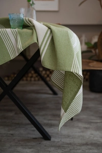 Close-up of green and white striped linen tablecloth showing natural fabric texture and drape
