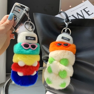 Close-up of colorful plush caterpillar keychains with sunglasses on a luxury handbag
