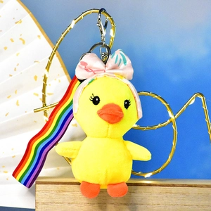 Detailed view of a cute yellow plush duck keychain with a pink bow and a colorful rainbow strap