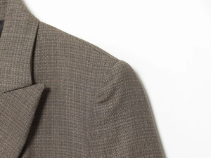 Detailed close-up of brown tweed blazer featuring notched lapels and padded shoulder seams
