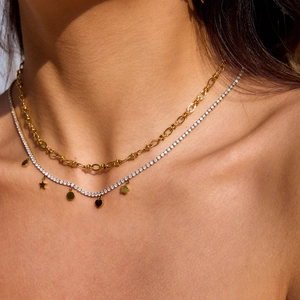 Detail of layered gold stainless steel necklace with tennis chain and star heart charms
