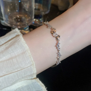 Close-up of a silver bow bracelet with sparkling zircons worn on a woman's wrist