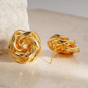 Close-up of golden metallic twisted flower earrings with polished hollow-out design