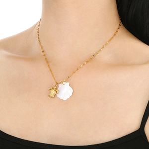 Detail of 18K gold-plated turtle and white shell pendants on a fine chain necklace