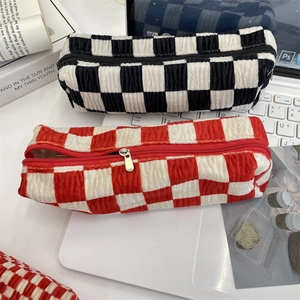 Detail of checkered velvet pouches with metal zippers in black and red patterns