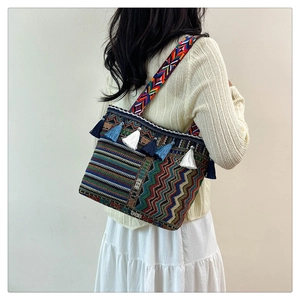 Detailed view of bohemian woven shoulder bag with colorful fringe and patterns on a model
