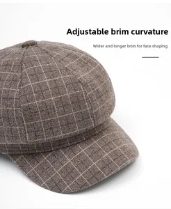 Detail of wide brim newsboy cap with brown plaid pattern and foldable curved peak