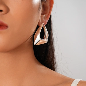 Close-up of model wearing irregular geometric silver earrings with polished mirror finish