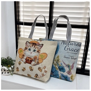 Close-up of canvas tote bags featuring cat and hummingbird prints with striped handles