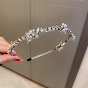Close-up of silver headband with rhinestone flowers and white pearls for women