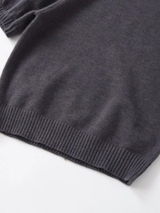 Detailed close-up of dark charcoal knit sweater with ribbed hem and soft texture