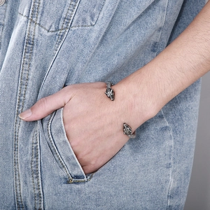 Detail of vintage silver wolf head cuff bracelet worn against blue denim background