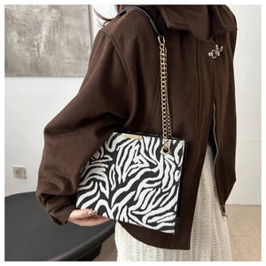 Detail of zebra pattern shoulder bag with gold chain strap on a vintage style outfit