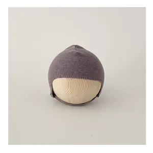 Detail of lilac knitted baby bonnet featuring side button and soft chin strap design