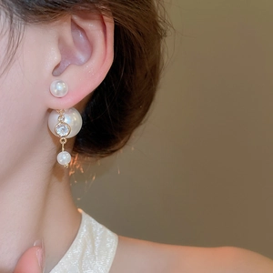 Detail of silver needle double-sided earrings with elegant pearls and cubic zirconia
