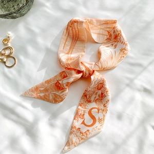 Silk scarf with orange animal print tied elegantly on white fabric with shadows