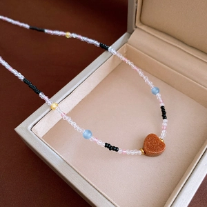 Detailed view of a glittering brown heart pendant on a multi-colored beaded necklace