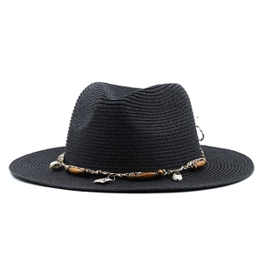 Detail of black straw Panama hat with wooden beads shell and leaf charm ornament