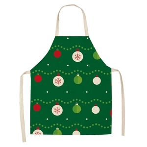 Detailed close-up of green linen Christmas apron with red festive ball and snowflake patterns