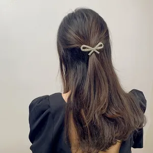 Close-up of sparkling rhinestone bow hair clip worn on elegant half-up hairstyle