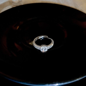 Macro shot of silver open ring featuring a central zircon and diamond-set band details