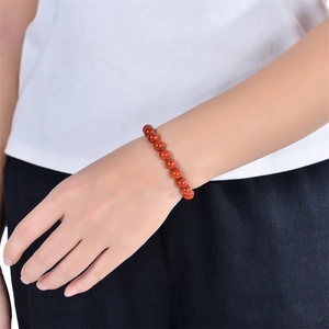 Detailed view of red stone beaded planet bracelet on wrist with elastic stretch cord