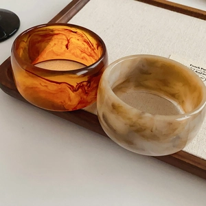 Detail of vintage acetate bangles in amber and marble patterns on a linen display tray