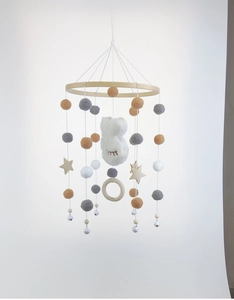 Detail of wooden baby mobile with plush bunny, felt balls, and stars for nursery decor