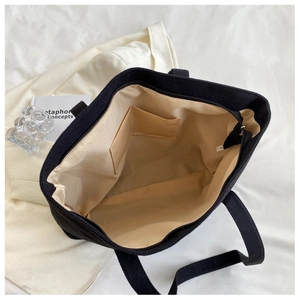 Internal view showing beige lining and interior pocket of a black canvas tote bag