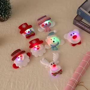 LED Christmas brooch set with Santa and snowman designs on cozy fabric background