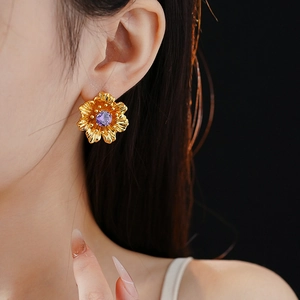 Detail of vintage gold flower earring with purple zircon stone worn by a model