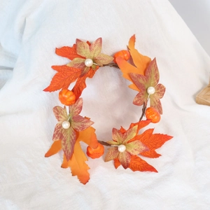 Close-up of autumn candle ring with maple leaves, mini pumpkins, and white pearls